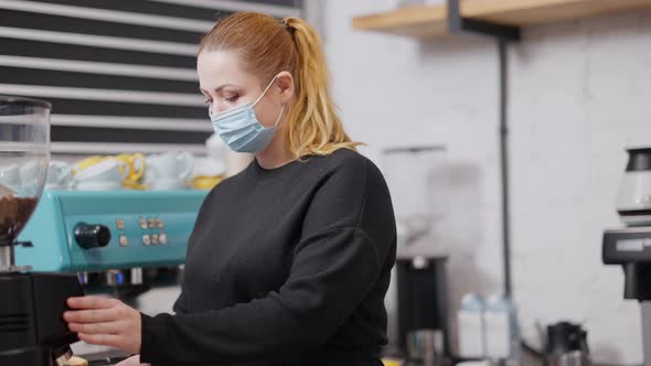 Middle Shot of Professional Female Barista in Covid19 Face Mask Preparing Coffee in Cafe alt