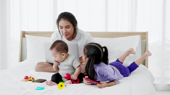 Busy single mom working from home and caring for her baby and little daughter alt