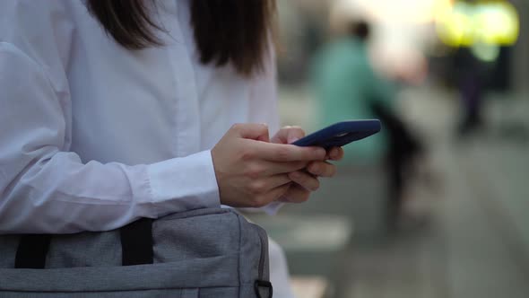 Hands of a Young Girl Typing a Text Message on a New Smartphone in the City alt
