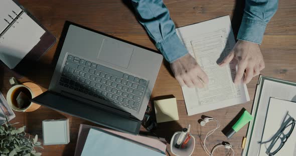 Office worker checking paperwork and using a laptop