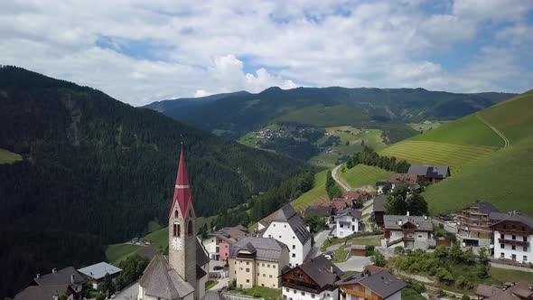 Aerial Flight Over the Bell Tower of a Church in the Dolomites alt