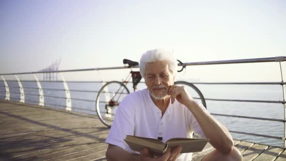 Senior Man Reading Book Sea at Sea Front Slow Motion alt