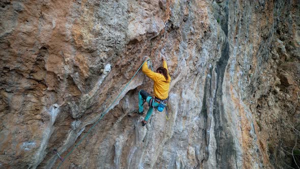 Slow Motion Back View Strong Man Rockclimber Climbs on Overhanging Limestone Crag with Colonets alt
