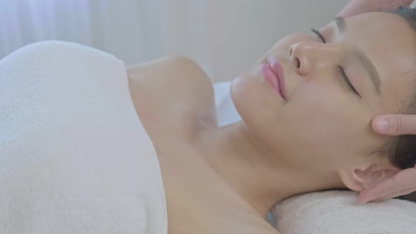 An young Asian woman lying down on a massage table in a spa at the resort during holiday.