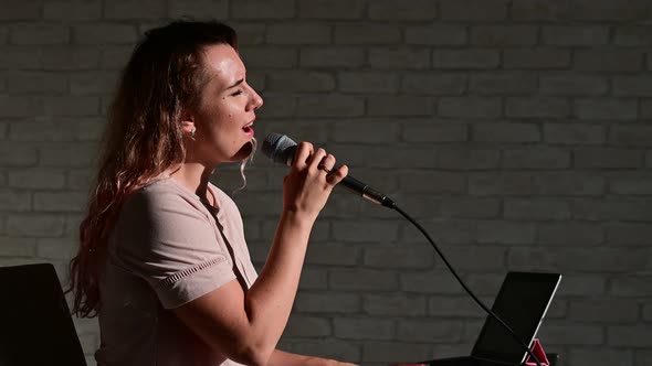 A Woman Records a Vocal Lesson Using a Laptop and Accompanying on a Keyboard While at Home alt