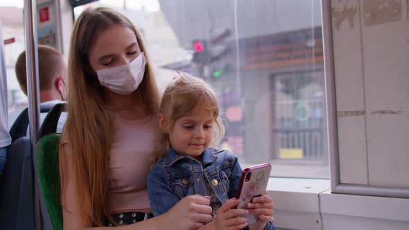 Tired Sleepy Woman with Daughter Going Home By Bus After Hard Work Day Child Kid Play on Smartphone alt