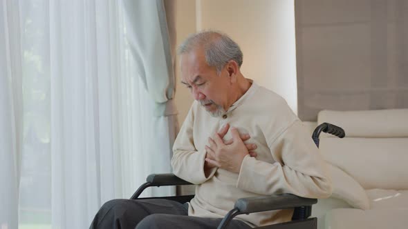 Asian Senior Elderly disabled man on wheelchair with chest pain suffer from heart attack in house. alt