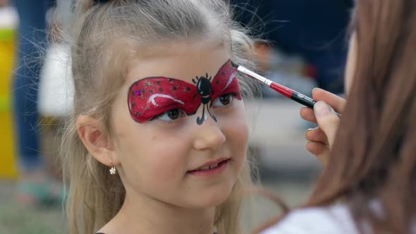 Cute  child girl getting face painted at the festival