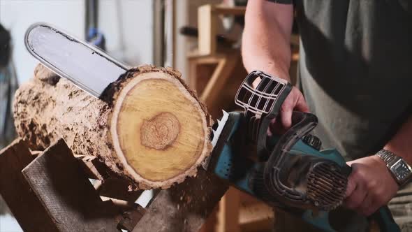 Man is Sawing a Wood with an Electrical Chainsaw at Carpentry Slow Motion