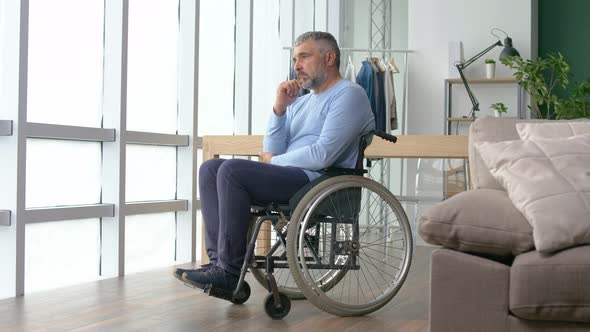 Man Looking Out the Window a Frustrated Mature Man Sitting in a Wheelchair alt