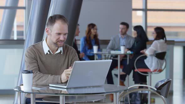 Young businessman using laptop computer in office lobby