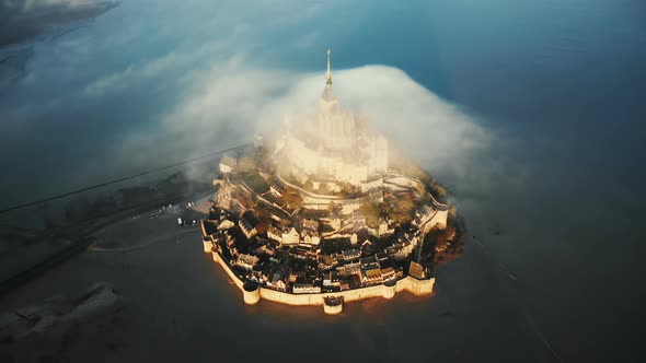 Top View Drone Flying High Around Majestic Sunrise Mont Saint Michel Island Castle with Cloud on Top alt