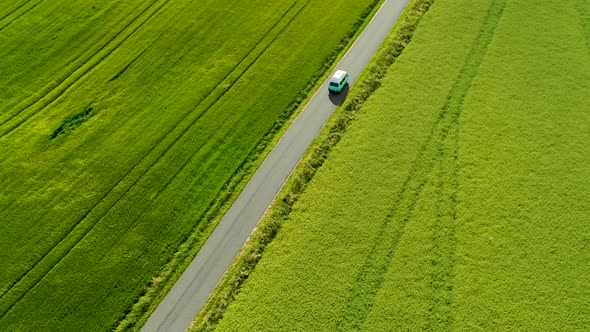 Mini Bus Driving On Narrow Country Road, With Green Fields On Both Sides, Drone Stock Footage 2x New alt