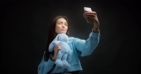 Young Asian Woman Makes Faces in Front of a Smartphone Taking Stupid Selfies