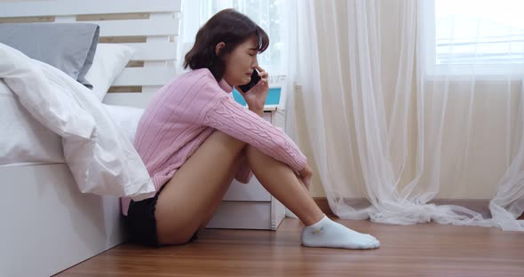 Young woman talking mobile phone and crying in bedroom