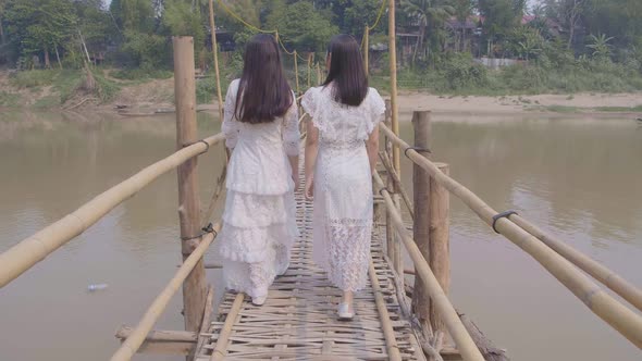 Two Girls Walking On Bamboo Bridge Cross River alt