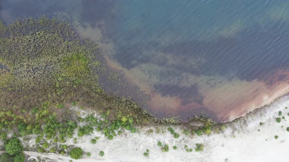 Aerial view at a beach with white sand and slow moving waves on the natural water with a clear view alt