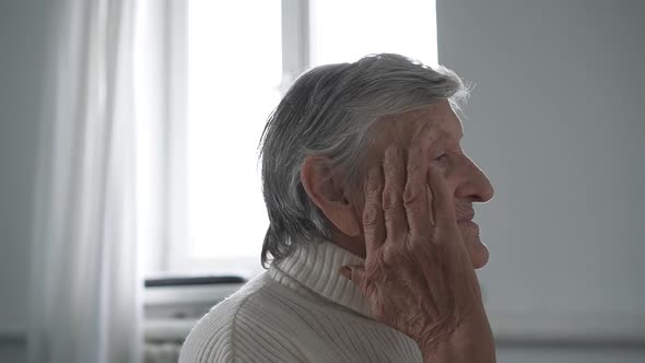 Old senior woman grandmother taking care of skin near eyes alt
