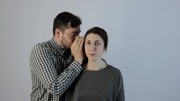 Young Man Whispers in a Young Woman's Ear alt