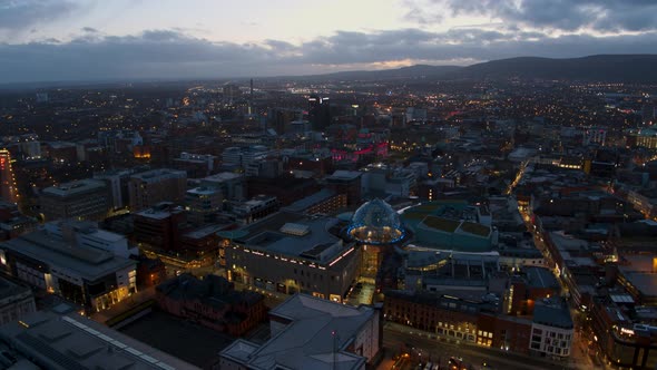 Aerial flyover of Belfast City Centre and Lagan River at night alt