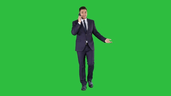 Successful man in suit speaks on phone and walks on a Green alt