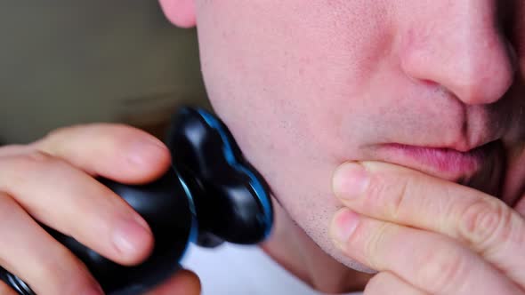 A man shaves with an electric razor close-up. Smooth shaving of light bristles. Slow Motion alt