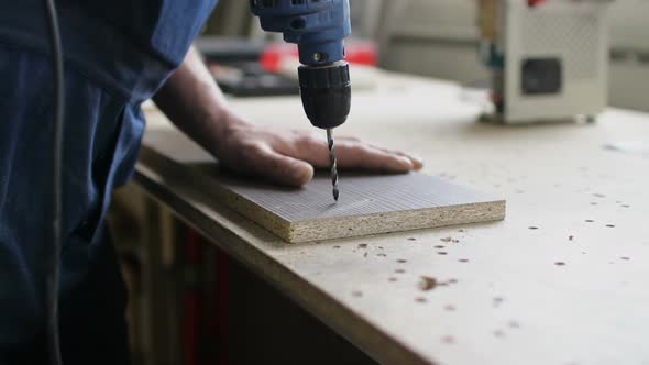 Man Hands Make Holes in Wooden Board with Electric Drill