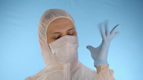 Man in Protective Suit and Medical Mask Straightens Rubber Gloves on Hands
