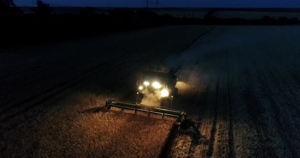 Combine harvester working on a wheat crop at night. Aerial view