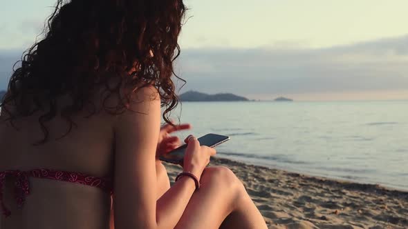 Girl with smartphone on the beach