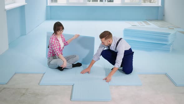 Female and Male Builders Make Floor Thermal Insulation Before Laying Laminate in Room During alt
