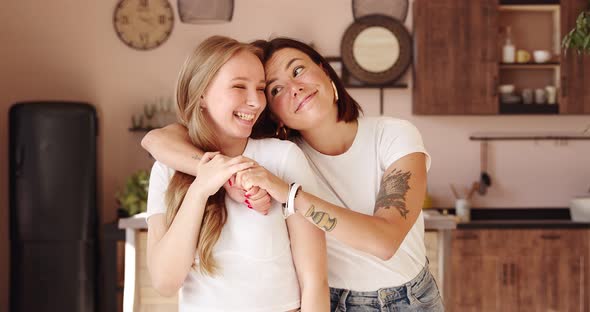 Two women friends hugging at home. Adorable lesbian couple. alt
