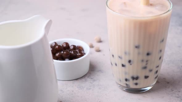 Cooking milk bubble tea with tapioca pearls in glass. alt