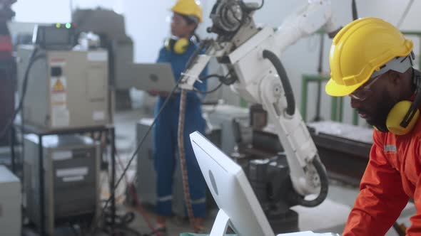 caucasian engineer technician control manage robot arm welding automation with computer monito
