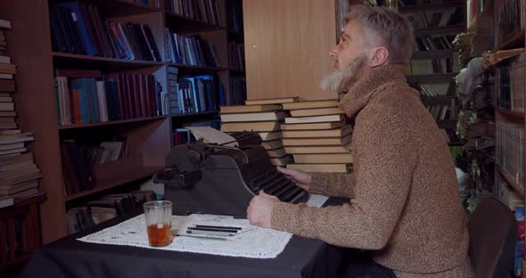 Ernest Hemingway is sitting at the desk and writing with a typewriter, 4k alt