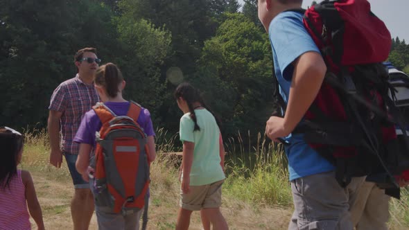 Kids at summer camp hiking by pond with leader