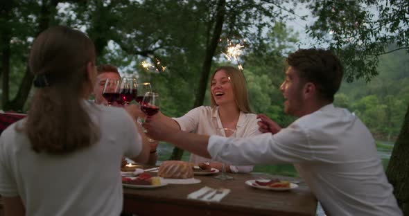 Youth Friendship Concept  Hands Toasting Red Wine Glass Beside River at Nightime alt