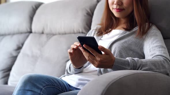 Young woman lying on sofa at living room and using cell phone at home