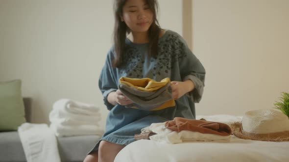 happiness travel asian female woman arrange cloth and stuff after checkin at hotel on the bed