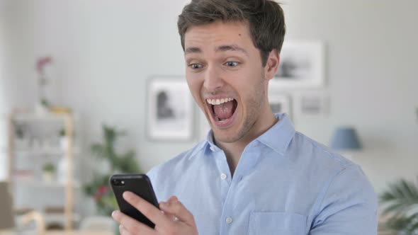Excited Man Enjoying Success while Using Smartphone alt
