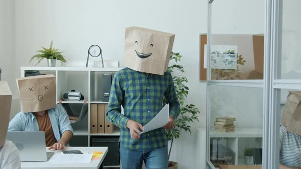 Businesspeople with Paper Bags on Heads Showing Emoji Busy with Paperwork in Office alt