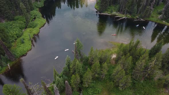 Counterclockwise drone shot of paddleboarders and kayakers coming around a bend in the Payette River alt