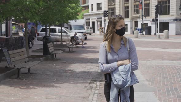 Girl walks alone on sidewalk with black protection mask during corona pandemic alt