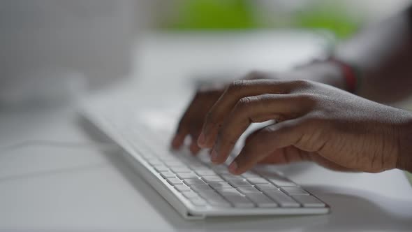 Closeup of African American Male Hands Typing on Computer Keyboard Indoors alt