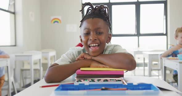 Video of happy african american boy sitting at school desk alt