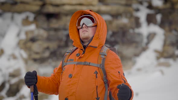 Male Rock Climber Is Wearing Sunglasses Is Standing in Mountains in Winter Day alt
