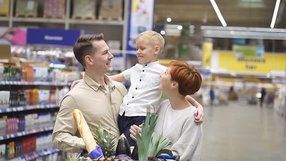 Portrait of Happy Young Family Shopping for Groceries in Supermarket Together with Little Boy