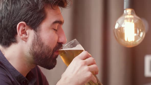 Bearded Young Man Drinks Beer and Having a Conversation with the Bartender alt