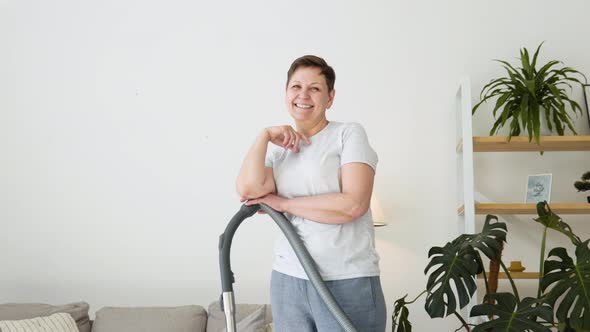 Portrait of a Senior Woman with a Vacuum Cleaner While Cleaning alt