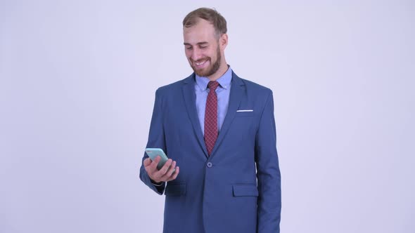 Happy Bearded Businessman Thinking While Using Phone